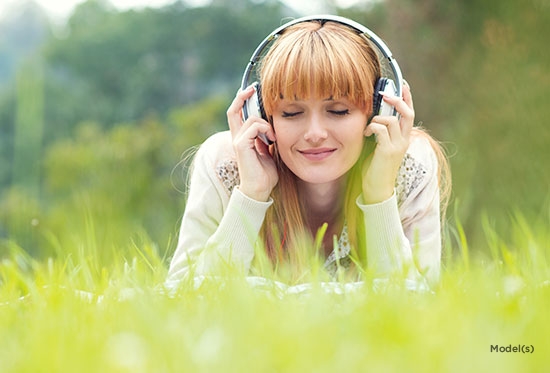 woman in field with headphones